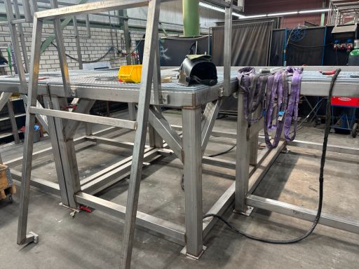Stalen frame met gereedschap en kettingen, opgesteld in een werkplaats.