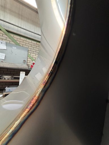 Close-up van een gebogen metalen rand met een glanzende afwerking.